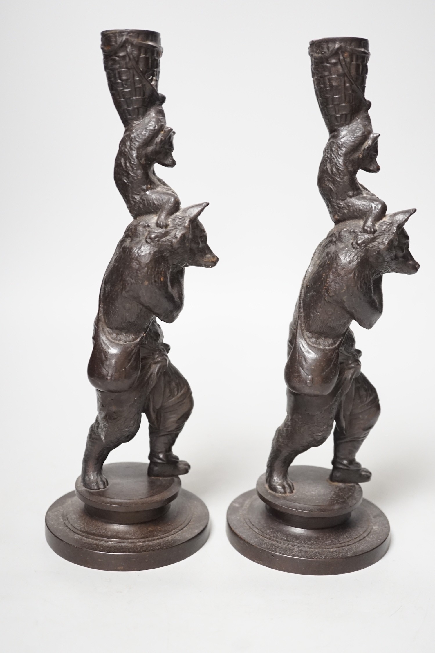 A pair of cast iron candlesticks in the form of anthropomorphised foxes and cubs. 27cm tall